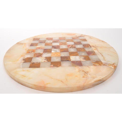 300 - A 20th Century marble circular chess board with central inlaid square board. In cream and red colour... 