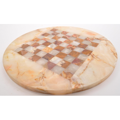 300 - A 20th Century marble circular chess board with central inlaid square board. In cream and red colour... 