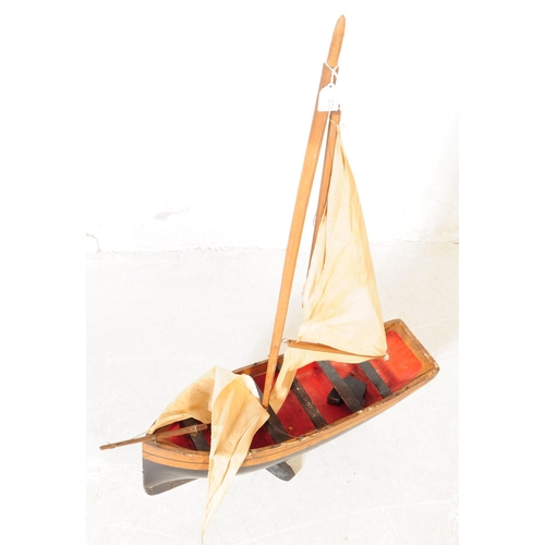 314 - An early 20th Century wood hand grooved and painted model / figure of a ship. Having red interior wi... 