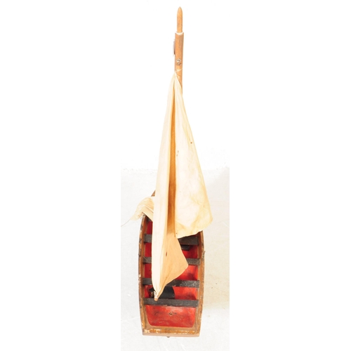 314 - An early 20th Century wood hand grooved and painted model / figure of a ship. Having red interior wi... 