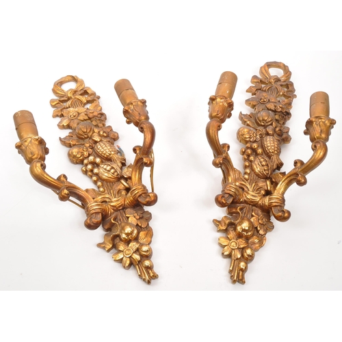 320 - A pair of 19th Century wooden gilt painted wall sconce lights. Each having twin scroll arms against ... 