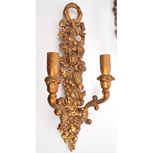 320 - A pair of 19th Century wooden gilt painted wall sconce lights. Each having twin scroll arms against ... 