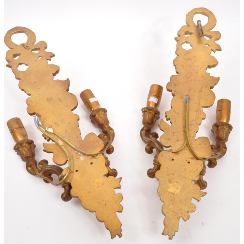 320 - A pair of 19th Century wooden gilt painted wall sconce lights. Each having twin scroll arms against ... 