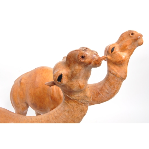 332 - A collection of four papier mache camel figures. Three standing examples with two sitting down. All ... 