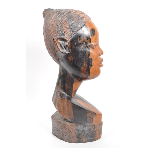 219 - A vintage 20th century African head bust. Depicting an African woman with carved features, raised on... 