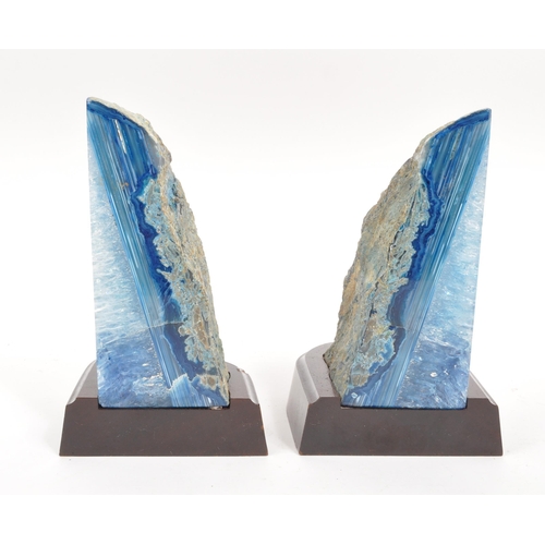 222 - A pair of agate bookends. Each bookend having a shaped mahogany base, with large blue agate geode at... 