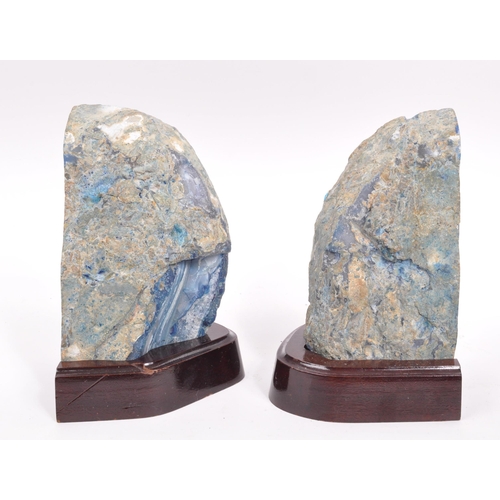 222 - A pair of agate bookends. Each bookend having a shaped mahogany base, with large blue agate geode at... 