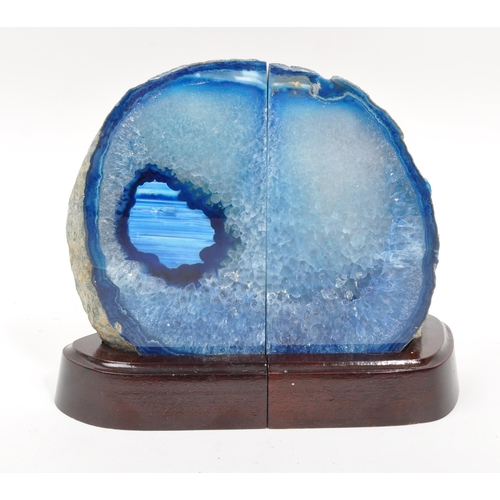 222 - A pair of agate bookends. Each bookend having a shaped mahogany base, with large blue agate geode at... 