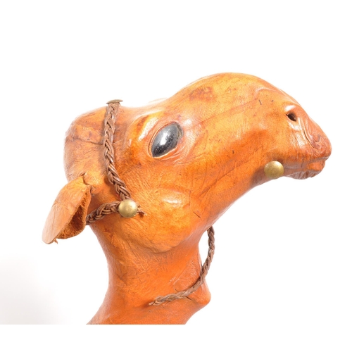 231 - A large 20th Century leather camel figure. The camel standing on all four legs head raised. In orang... 