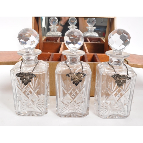 243 - A mid Century teak tantalus with three crystal glass decanters in lockable wooden case with set of g... 