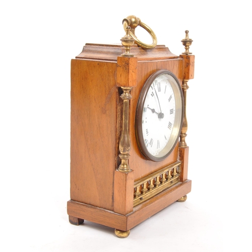 302 - An Edwardian walnut mantel clock with brass columns to either side and brass finials to the front co... 