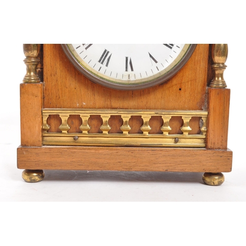 302 - An Edwardian walnut mantel clock with brass columns to either side and brass finials to the front co... 