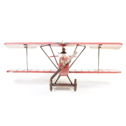 384 - A large 20th century carved wooden aeroplane model. The model painted in a red colourway, in the for... 