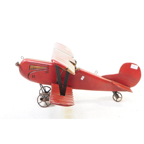 384 - A large 20th century carved wooden aeroplane model. The model painted in a red colourway, in the for... 