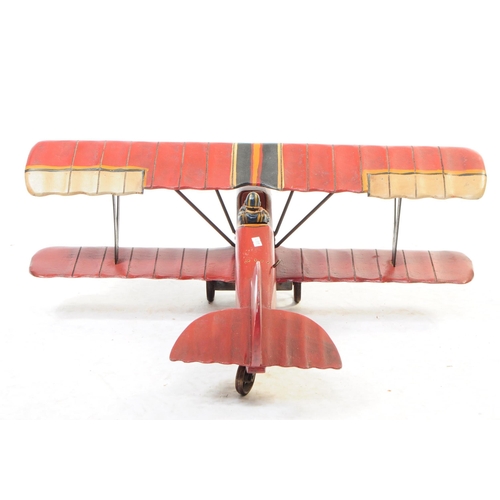 384 - A large 20th century carved wooden aeroplane model. The model painted in a red colourway, in the for... 