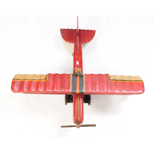 384 - A large 20th century carved wooden aeroplane model. The model painted in a red colourway, in the for... 