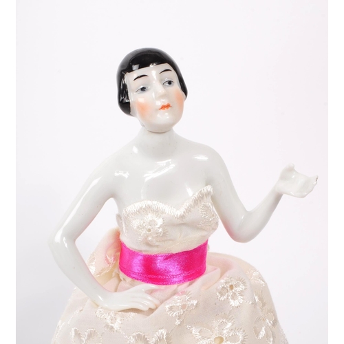 10 - An early 20th century porcelain china pin / half doll. Having a three layer pierced dress, pin ribbo... 