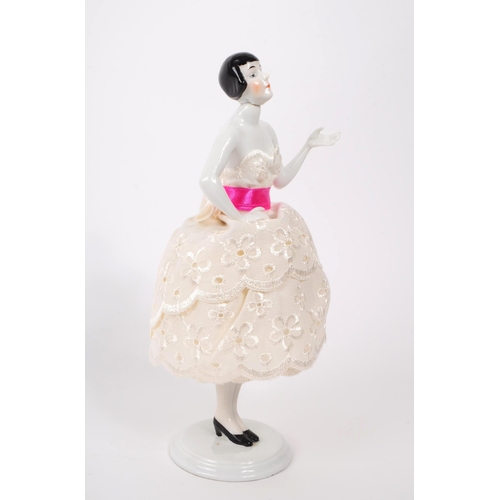 10 - An early 20th century porcelain china pin / half doll. Having a three layer pierced dress, pin ribbo... 