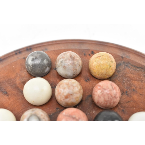 83 - A figured walnut solitaire circular board with polished hardstone geological specimen marbles. The b... 