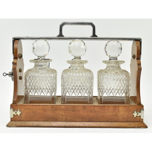 156 - A Victorian late 19th century oak & silver plated three decanters tantulus. The tantulus having ... 