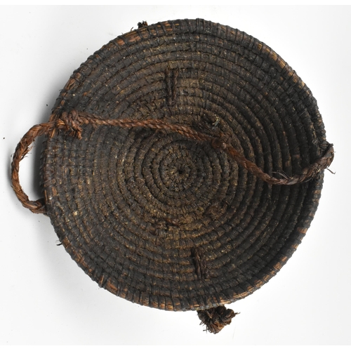 86 - An African tribal straw helmet hat. The dome shaped straw hat decorated with two wooden carved faces... 