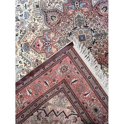 264 - A Persian Heriz hand woven wool floor carpet rug. The carpet having a central pink medallion of geom... 