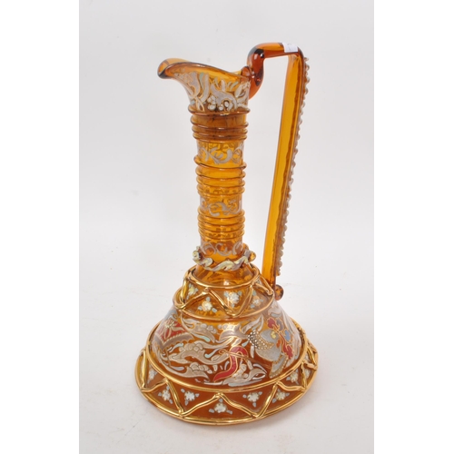 16 - A vintage 20th century amber glass ewer, with geometric and swirling gilt decoration, including hand... 