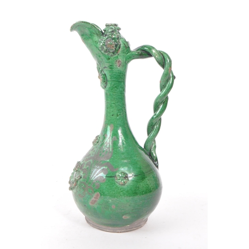 20 - A 19th century Turkish Ottoman canakkale pottery ewer, with a green glaze. Featuring a braided handl... 