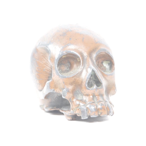 212 - A vintage 20th century small bronzed metal cast skull. Showing signs of a painted coating to the sur... 