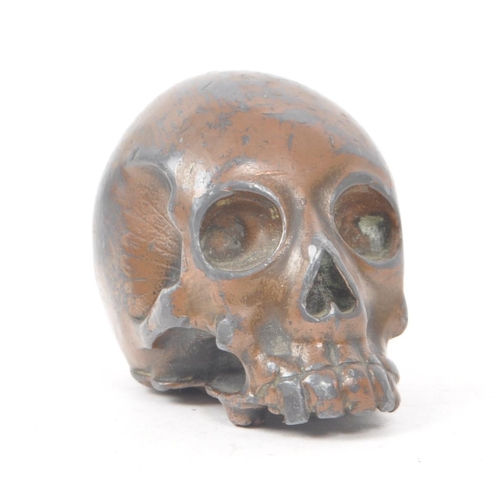 212 - A vintage 20th century small bronzed metal cast skull. Showing signs of a painted coating to the sur... 