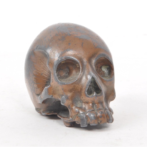 212 - A vintage 20th century small bronzed metal cast skull. Showing signs of a painted coating to the sur... 