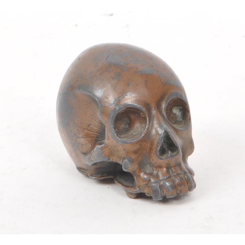 212 - A vintage 20th century small bronzed metal cast skull. Showing signs of a painted coating to the sur... 