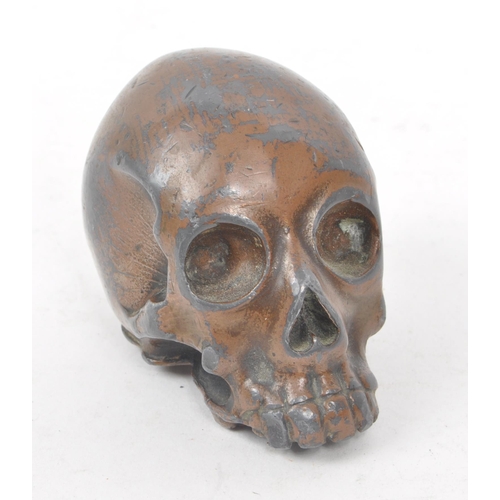 212 - A vintage 20th century small bronzed metal cast skull. Showing signs of a painted coating to the sur... 