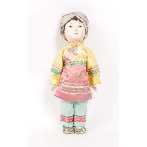 222 - A vintage 1950s Chinese doll, with hard plastic head and hands, dressed in pink, yellow and blue tra... 