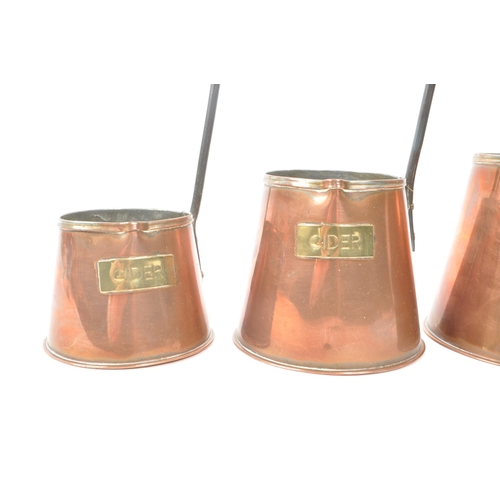 253 - Set of three copper cider measures graduating in size, each with a long hook handle and brass plaque... 