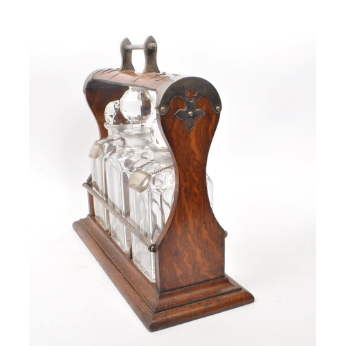 254 - A wooden early 20th/ 19th century tantalus with metal detailing. Comes with three cut glass decanter... 