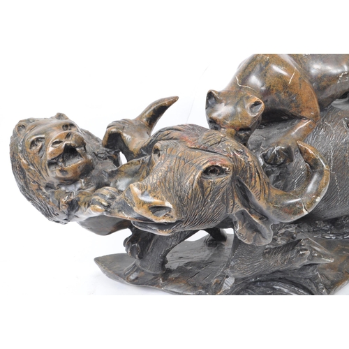 294 - A large believed South African 20th century carved soapstone sculpture of lions slaying a buffalo. T... 