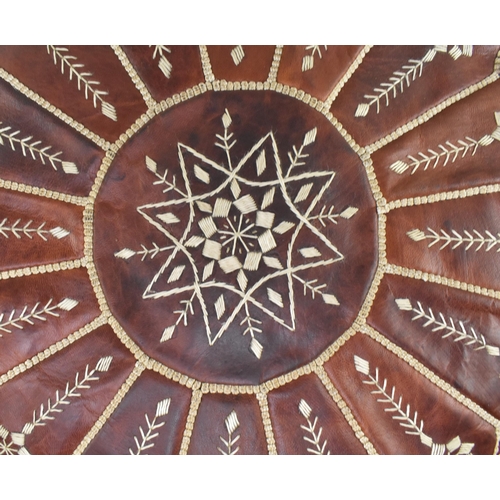 224 - A Moroccan Northern African tan brown leather and white stitching decorative footstool / pouffe. The... 