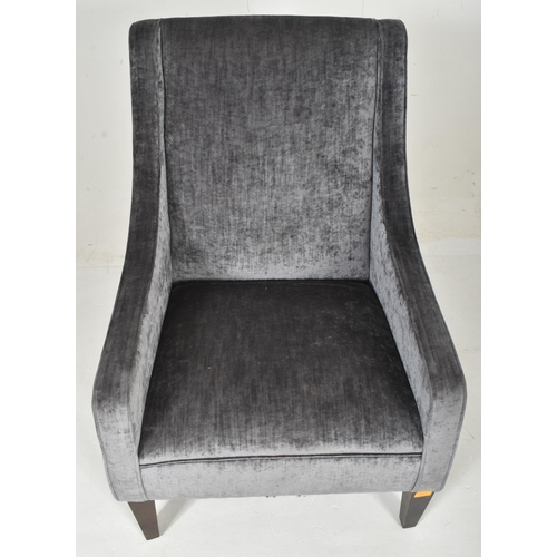 310 - A contemporary British Design armchair. The chair having a padded seat and backrest with low armrest... 