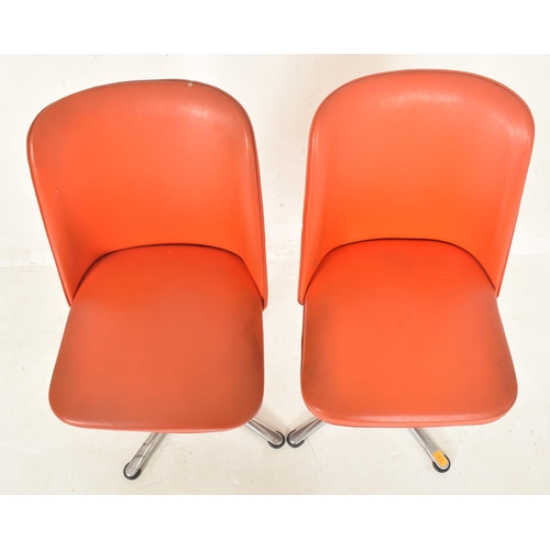 381 - A pair of retro late 20th century orange leatherette swivel office chairs. Each having a curved back... 