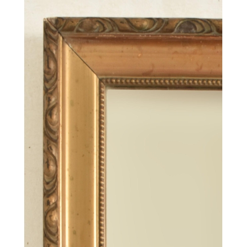 286 - An early 20th century gilt wood framed hanging mirror. The mirror of rectangular form with a gadroon... 