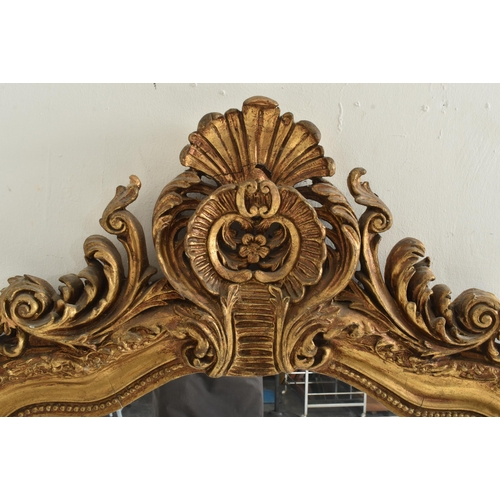 377 - A large 20th century gilt resin hanging wall mirror in the Rococo style. The mirror having a floral ... 