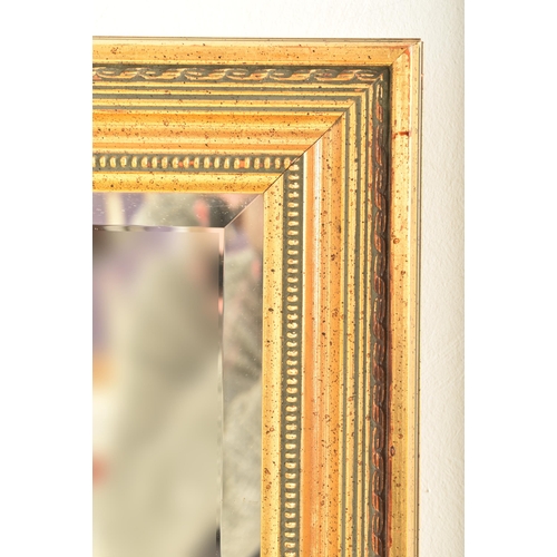 599 - A large contemporary gilt framed hanging mirror. The mirror of rectangular form having a gilt cushio... 