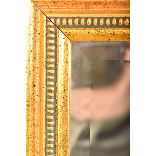 599 - A large contemporary gilt framed hanging mirror. The mirror of rectangular form having a gilt cushio... 