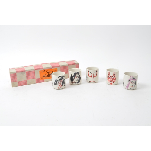 115 - A set of five mid-century Japanese Kabuki style sake / shot porcelain cups, housed within their orig... 