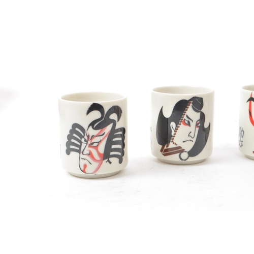 115 - A set of five mid-century Japanese Kabuki style sake / shot porcelain cups, housed within their orig... 