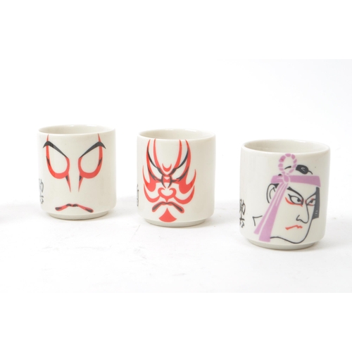 115 - A set of five mid-century Japanese Kabuki style sake / shot porcelain cups, housed within their orig... 