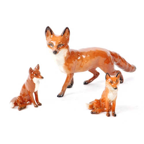 14 - Beswick - Three 20th century porcelain fox figurines, comprising of a walking adult fox, with two si... 