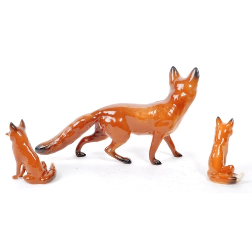 14 - Beswick - Three 20th century porcelain fox figurines, comprising of a walking adult fox, with two si... 