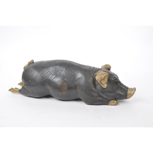 201 - A vintage 20th-century bronze figure of a pig lying down, with gilt detailing to the feet, nose, tai... 